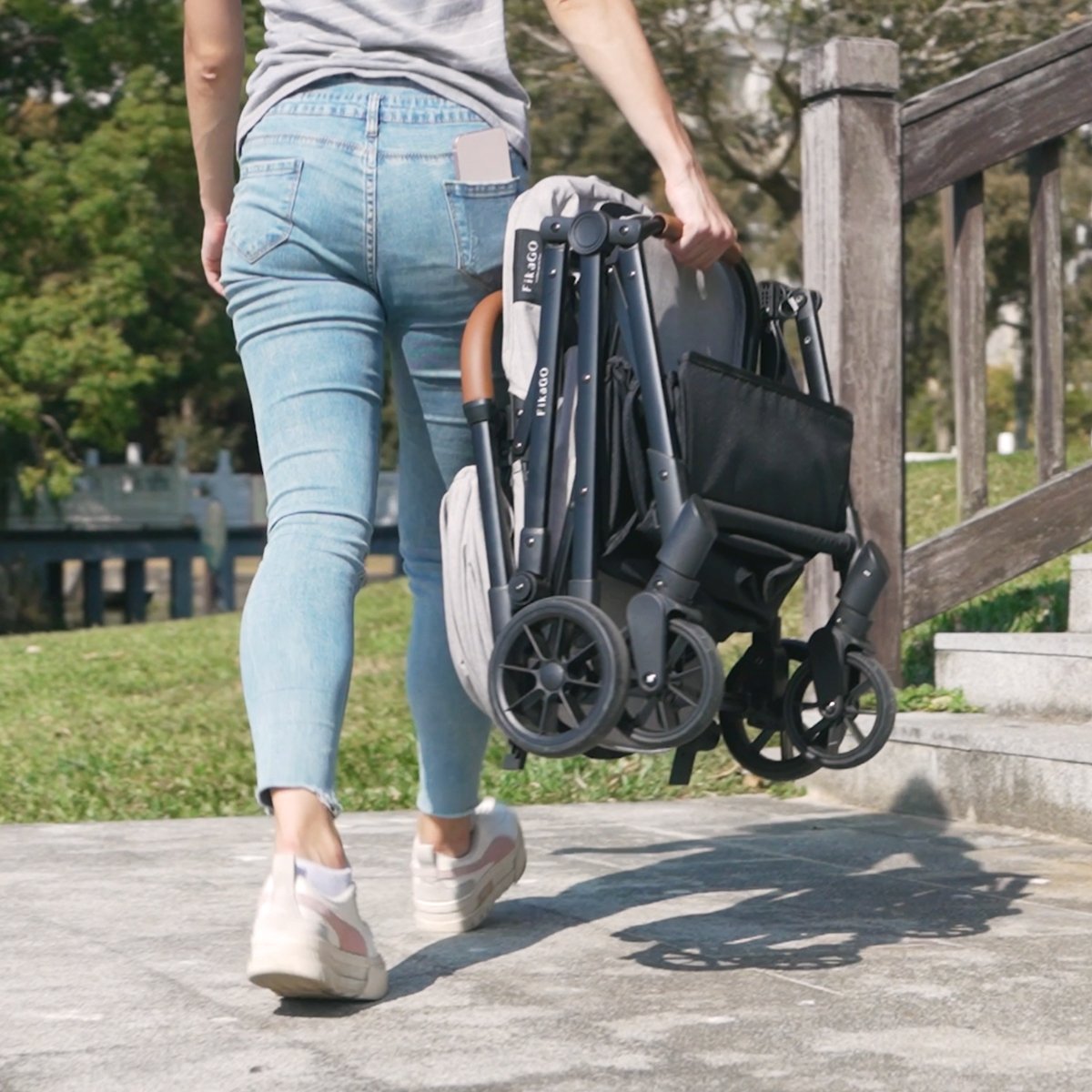 A lady is carrying a folded FikaGO FREE TO GO pet stroller