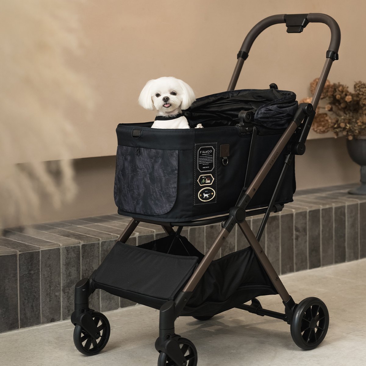 A small dog is sitting in FikaGO FREE TO GO 2 stroller in black