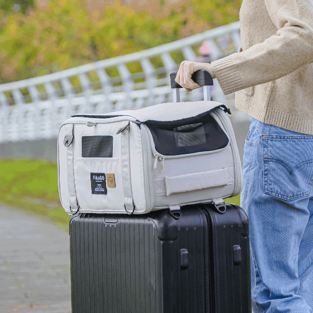 Person pushing a suitcase with FikaGO TRUFFLE carry-on pet bag attached via luggage handle sleeve