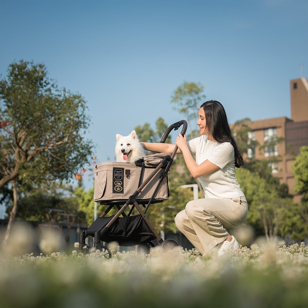 FikaGO FREE TO GO 2 pet stroller with a white dog and its owner in a garden in sandy beige